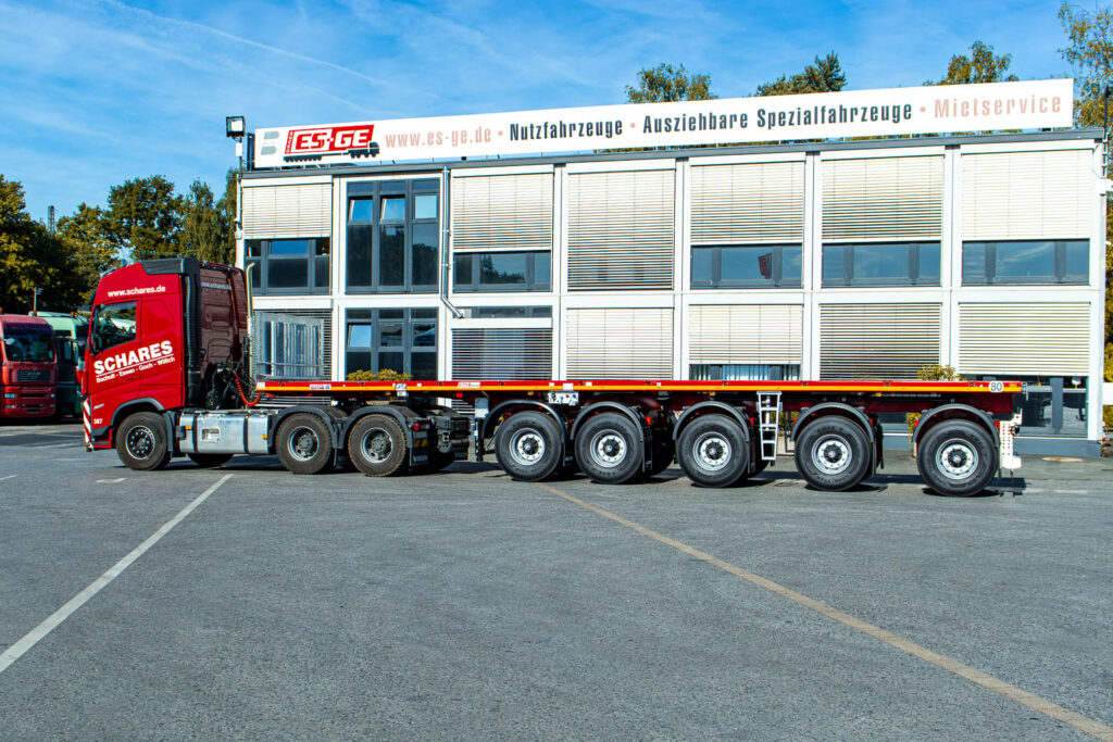 Sattelzugmaschine mit aufgesatteltem MAX Trailer MAX410 Ballastauflieger mit fünf Achsen, aufgenommen von der Fahreseite. Der komplette Zug steht hinter dem Hauptgebäude der ES-GE.
