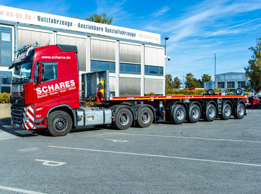 Sattelzugmaschine mit aufgesatteltem MAX Trailer MAX410 Ballastauflieger mit fünf Achsen, aufgenommen von der Fahreseite. Der komplette Zug steht hinter dem Hauptgebäude der ES-GE.
